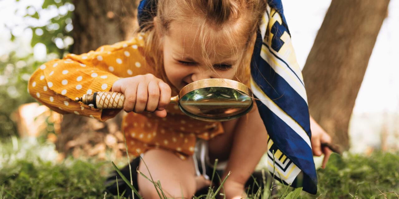 girl playing outside with magnifying glass